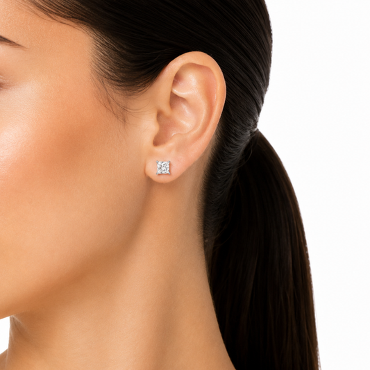 Close-up of an ear wearing diamond stud earrings with a white background