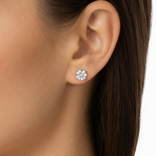 Close-up of an ear wearing a diamond stud earring with a blurred background