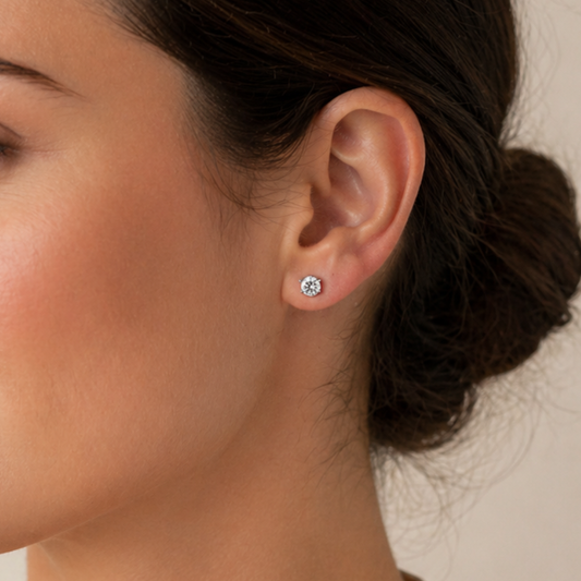 Close-up of an ear wearing a diamond stud earring with a blurred background