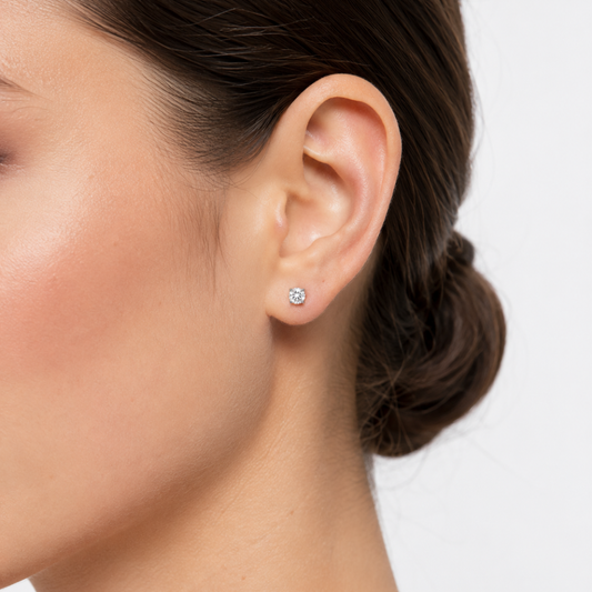 Close-up of an ear wearing a diamond stud earring on a plain background