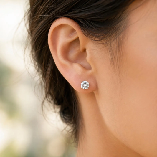 Close-up of an ear wearing a diamond stud earring with blurred background