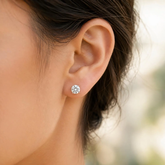 Close-up of an ear wearing a diamond stud earring with blurred background