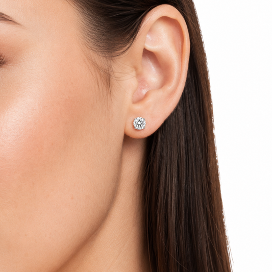 Close-up of an ear wearing a diamond stud earring on a white background