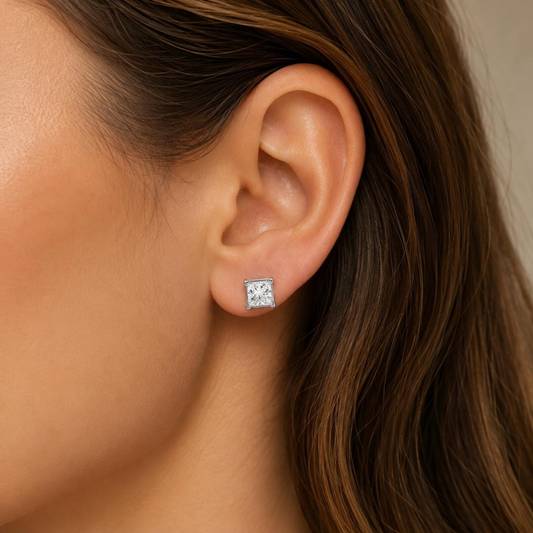 Close-up of an ear wearing a diamond stud earring with brown hair.