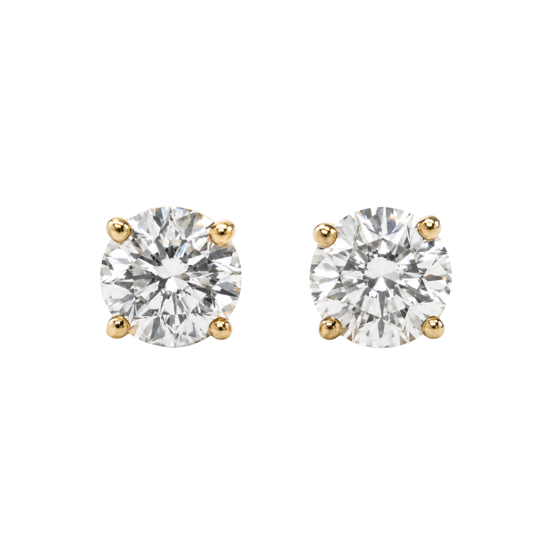 Pair of diamond stud earrings with yellow gold prongs on a white background