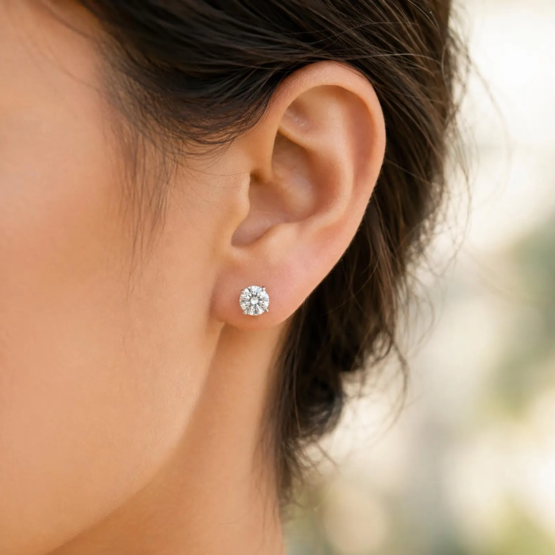 Close-up of an ear wearing a diamond stud earring with blurred background