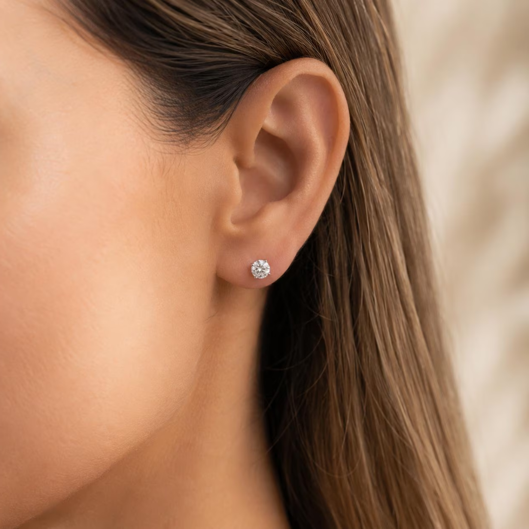 Close-up of an ear wearing a diamond stud earring with blurred background