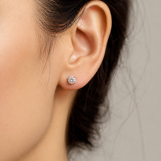 Close-up of an ear wearing a diamond stud earring with a neutral background